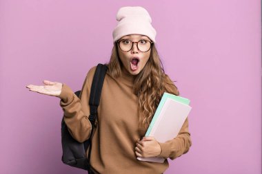 İspanyol güzel kadın şaşırmış ve şok olmuş görünüyor. Çenesi düşmüş ve elinde bir nesne var. Üniversite öğrencisi konsepti