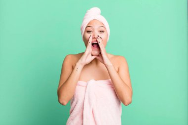 İspanyol güzel kadın kendini mutlu hissediyor, elleri ağızının yanında bornoz giyerek bağırıyor. güzellik konsepti