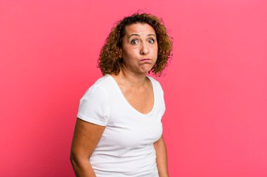 Orta yaşlı, şapşal, çılgın, şaşırmış bir ifadesi olan, yanakları şişen, doldurulmuş, şişman ve yemek dolu bir İspanyol kadın.