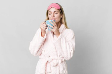 pretty caucasian woman wearing night wear and having a coffee cup for breakfast