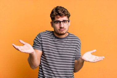 young adult caucasian man feeling puzzled and confused, unsure about the correct answer or decision, trying to make a choice