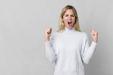 caucasian blonde woman shouting aggressively with an angry expression. copy space concept