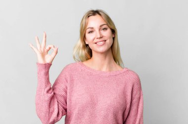caucasian blonde woman feeling happy, showing approval with okay gesture