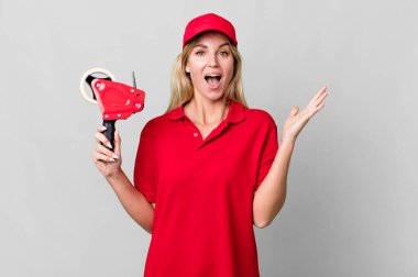 caucasian blonde woman feeling happy and astonished at something unbelievable. shipping packer concept