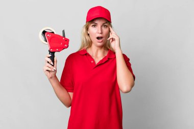 caucasian blonde woman looking surprised, realizing a new thought, idea or concept. shipping packer concept