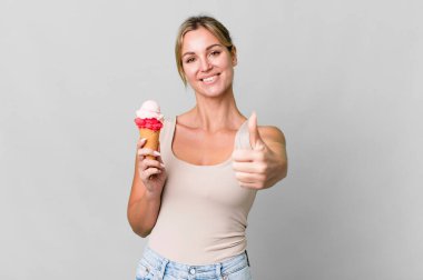 caucasian blonde woman feeling proud,smiling positively with thumbs up. ice cream concept