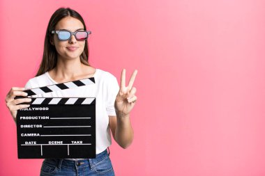 Genç, güzel bir bayan gülümsüyor ve iki numarayı gösteriyor. Sinema filmi veya film konsepti