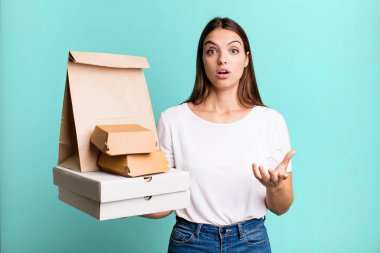 Genç ve güzel bir kadın şok olmuş ve şaşırmış hissediyor. teslimat ve paket konsepti