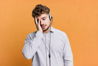young adult caucasian man feeling bored, frustrated and sleepy after a tiresome. telemarketer agent concept