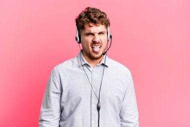 young adult caucasian man feeling disgusted and irritated and tongue out. telemarketer agent concept