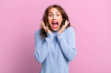 Genç ve güzel bir kadın beklenmedik bir sürpriz yüzünden şaşkın, heyecanlı, gülen, şaşkın ve mutlu hissediyor.