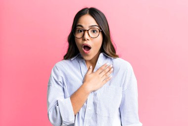 İspanyol güzel kadın şaşkın ve şaşırmış hissediyor, gülümsüyor, el ele tutuşuyor, mutlu ya da minnettarlık gösteriyor.