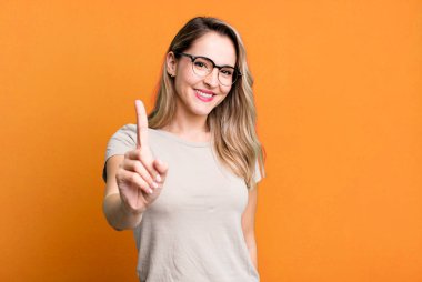 Gururla ve kendinden emin bir şekilde gülümseyerek bir numaralı pozu vererek, bir lider gibi hissederek.