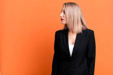 pretty blonde woman on profile view thinking, imagining or daydreaming. businesswoman concept