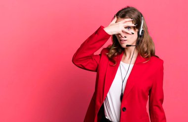 caucasian pretty woman looking shocked, scared or terrified, covering face with hand. telemarketer agent concept