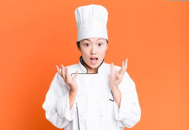 pretty asian woman feeling extremely shocked and surprised. restaurant chef concept