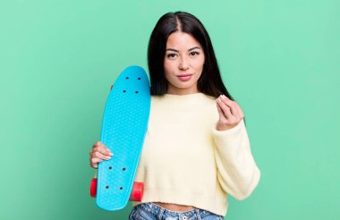 hispanic pretty woman making capice or money gesture, telling you to pay. skate boarding concept