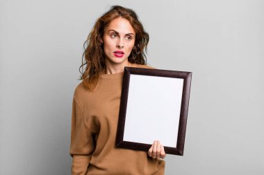 İspanyol güzel kadın üzgün, üzgün ya da kızgın hissediyor ve boş bir çerçeveyle yan tarafa bakıyor.