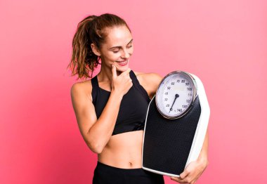 Mutlu, kendine güvenen, elleri çenesinde gülümseyen İspanyol güzel kadın. fitness, diyet ve ağırlık ölçeği kavramı