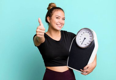 hispanic pretty woman feeling proud,smiling positively with thumbs up. fitness and diet concept
