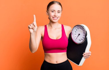 Kafkasyalı güzel kadın gülümsüyor ve arkadaş canlısı görünüyor, bir numarayı gösteriyor. fitness ve diyet konsepti