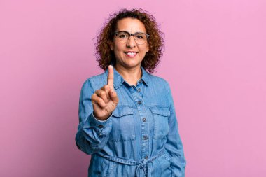 Orta yaşlı İspanyol bir kadın gülümsüyor ve arkadaş canlısı görünüyor. Bir numara ya da ilk eli önde, geriye doğru sayıyor.