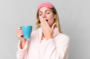 pretty caucasian woman wearing night wear and having a coffee cup for breakfast