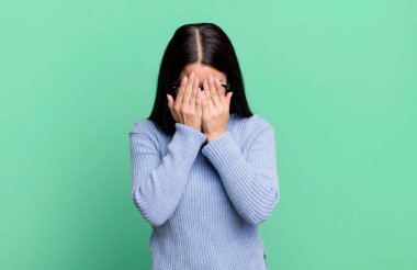 Güzel Latin bir kadın üzgün, hayal kırıklığına uğramış, gergin ve depresif, iki eliyle yüzünü kaplayan, ağlayan