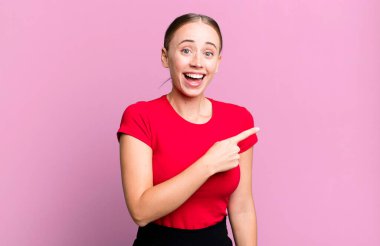 Heyecanlı ve şaşırmış görünüyor. Yana ve yukarıya bakıyor. Boşluğu kopyalıyor.