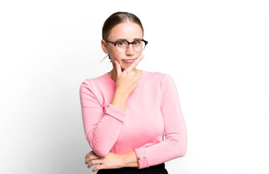 Ciddi görünüyor, düşünceli ve güvensiz, bir kolu çaprazlanmış ve eli çenesinde, seçenekleri değerlendiriyor.