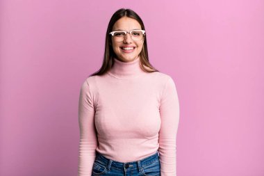 Güzel, genç bir kadın neşeli ve kendinden emin bir şekilde gülüyor, mutlu, dostane bir gülümsemeyle.