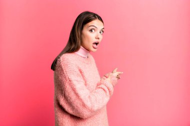 Güzel, genç bir kadın şaşkın ve şaşırmış hissediyor. Yandaki fotokopi alanını işaret ediyor. Şaşırmış, ağzı açık bir bakışla.