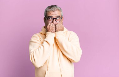 Orta yaşlı bir adam endişeli, stresli ve korkmuş görünüyor, tırnak yiyor ve yanal fotokopi alanı arıyor.