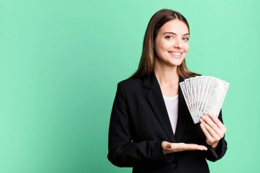 Genç, güzel bir kadın neşeyle gülümsüyor, mutlu hissediyor ve bir konsept gösteriyor. iş ve dolar banknotları kavramı