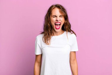 Genç ve güzel bir kadın agresif bir şekilde bağırıyor, kızgın, sinirli, öfkeli ya da sinirli görünüyor.