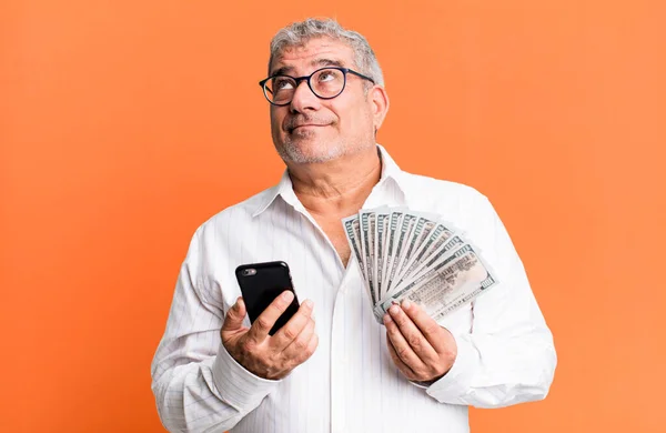middle age senior man with a smartphone and dollar banknotes