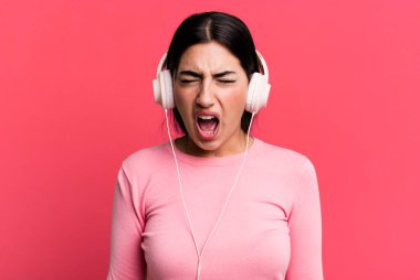 shouting aggressively, looking very angry. listening music with headphones