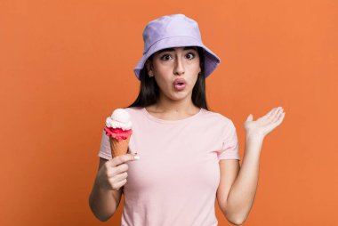 Şaşırmış ve şok olmuş bir şekilde, çenesi düşmüş bir şekilde elinde bir nesne tutarken. dondurma ve yaz konsepti