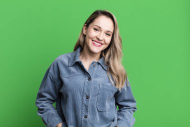 Olumlu, mutlu, kendinden emin ve rahat bir ifadeyle neşeyle gülümsüyor.