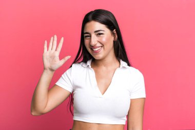 Gülümsüyor ve dost canlısı görünüyor, 5 ya da 5 numarayı gösteriyor, el önde, geriye doğru sayıyor.