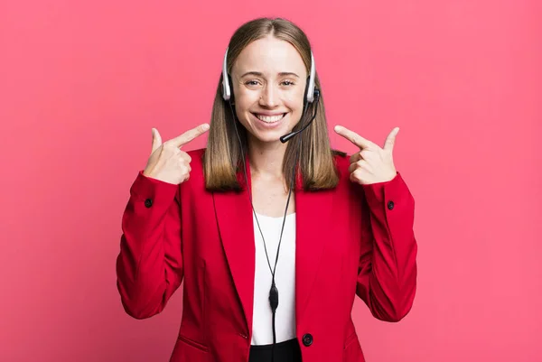 smiling confidently pointing to own broad smile. telemarketer concept