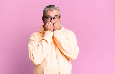 Orta yaşlı bir adam endişeli, stresli ve korkmuş görünüyor, tırnak yiyor ve yanal fotokopi alanı arıyor.