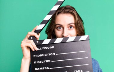 Genç ve güzel bir kadın, elinde alkışlı bir sinema tahtası tutuyor.