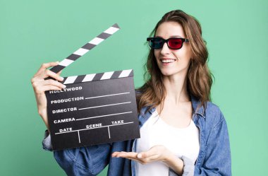 Genç ve güzel bir kadın, elinde alkışlı bir sinema tahtası tutuyor.