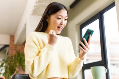 asian pretty woman using a smartphone in a cool home