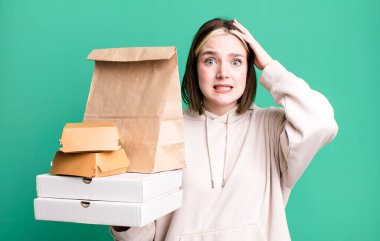 young pretty woman feeling stressed, anxious or scared, with hands on head. take away fast food concept