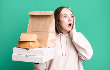 young pretty woman feeling happy, excited and surprised. take away fast food concept