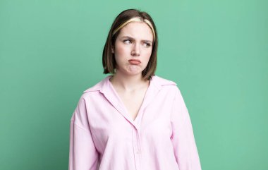 Genç, güzel bir kadın üzgün, üzgün ya da kızgın hissediyor ve yan tarafa bakıyor.