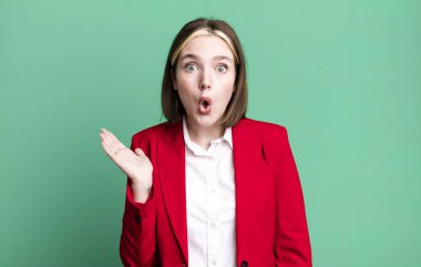 Genç ve güzel bir kadın şaşırmış ve şok olmuş görünüyor. Çenesi düşmüş ve elinde bir nesne tutuyor. iş kavramı