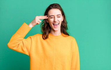 Genç ve güzel bir kadın mutsuz ve stresli görünüyor, intihar jesti silah işareti yapıyor